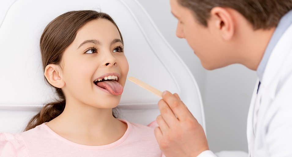 Doctor using inspection spatula to examine patient throat. ENT doctor doing throat exam. patient opened his mouth to throat check-up